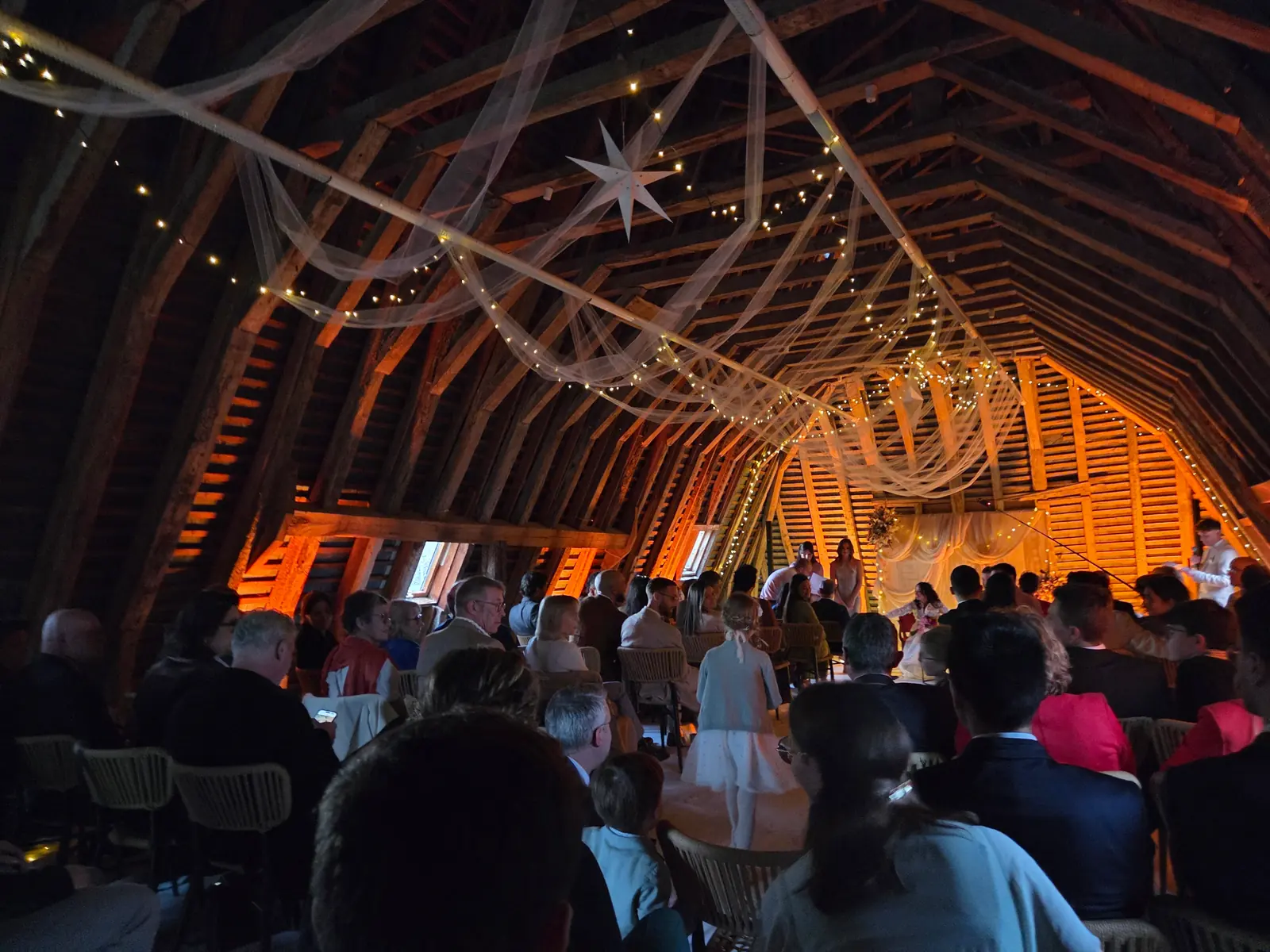 Grange de réception décorée de voilages et de guirlandes lumineuses