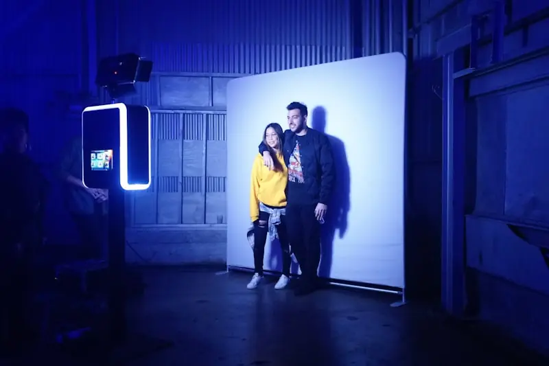 Couple posant devant le fond blanc de la borne photo lors d'une soirée de mariage